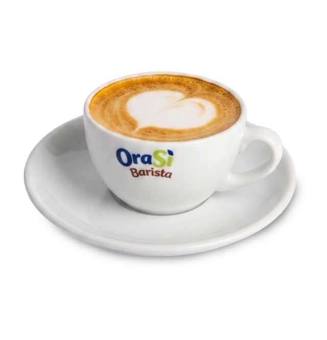 Xícara branca de cappuccino com latte art em formato de coração, rótulo "OraSì Barista", no pires combinando, fundo b...