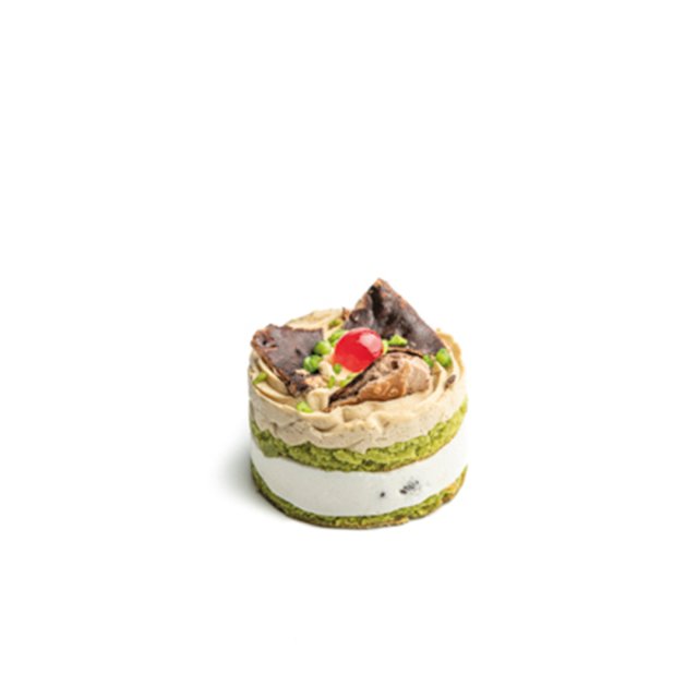 Pequeno bolo redondo em camadas de pistache verde e creme branco, com chantilly, cereja e chocolate